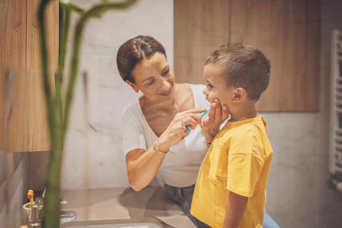 Woman brushing child's teeth