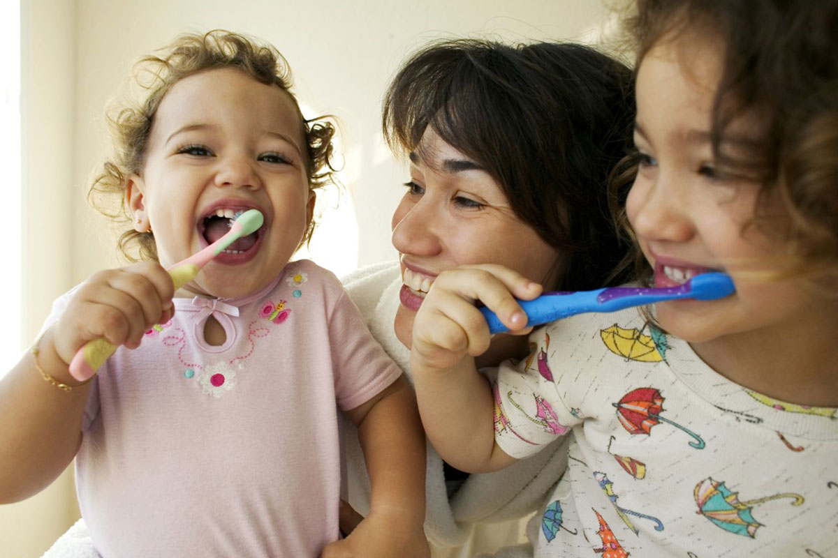 Children brushing their teeth with their mum and learning about dental myths